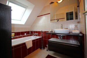 Salle de bain privative de la chambre Sterenn, avec baignoire et faïence beige et rouge